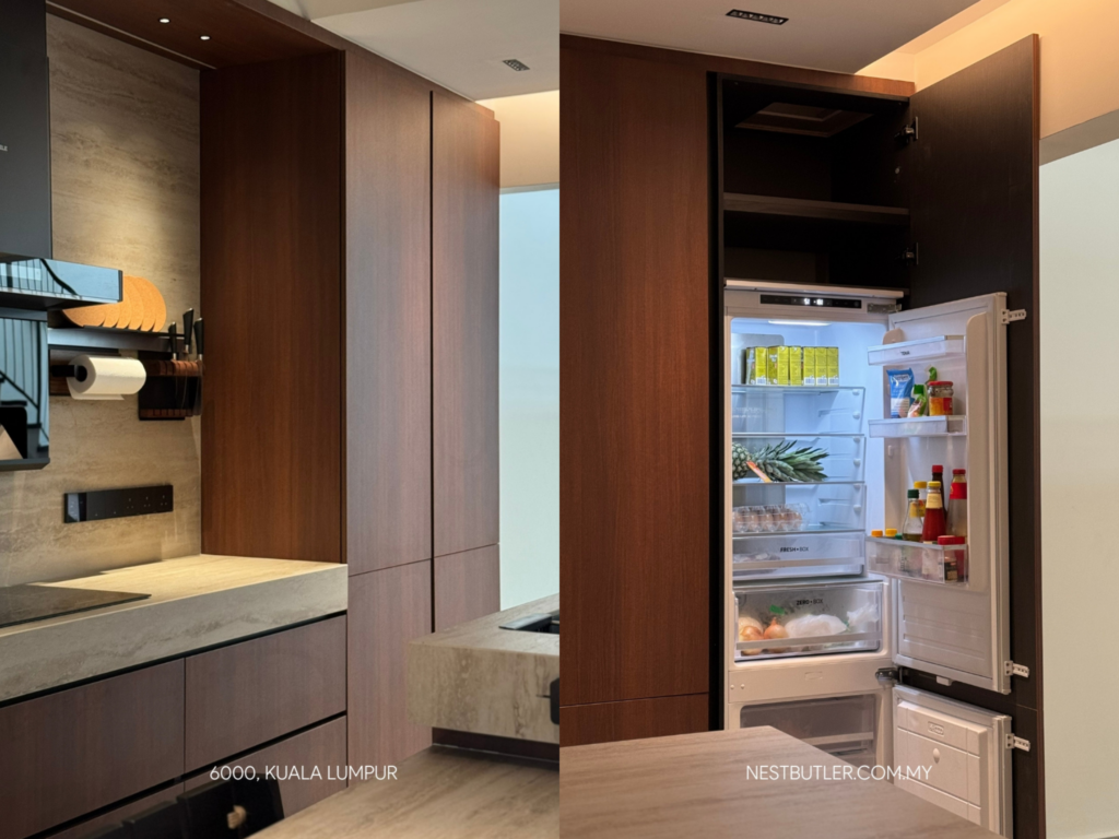 Modern Kuala Lumpur kitchen with warm wood cabinetry and a built-in refrigerator hidden behind a tall cabinet door, shown open with organised shelves and condiments.