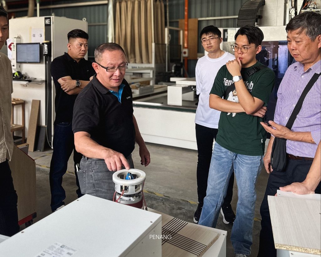 Group inspecting machinery part during a manufacturing facility tour