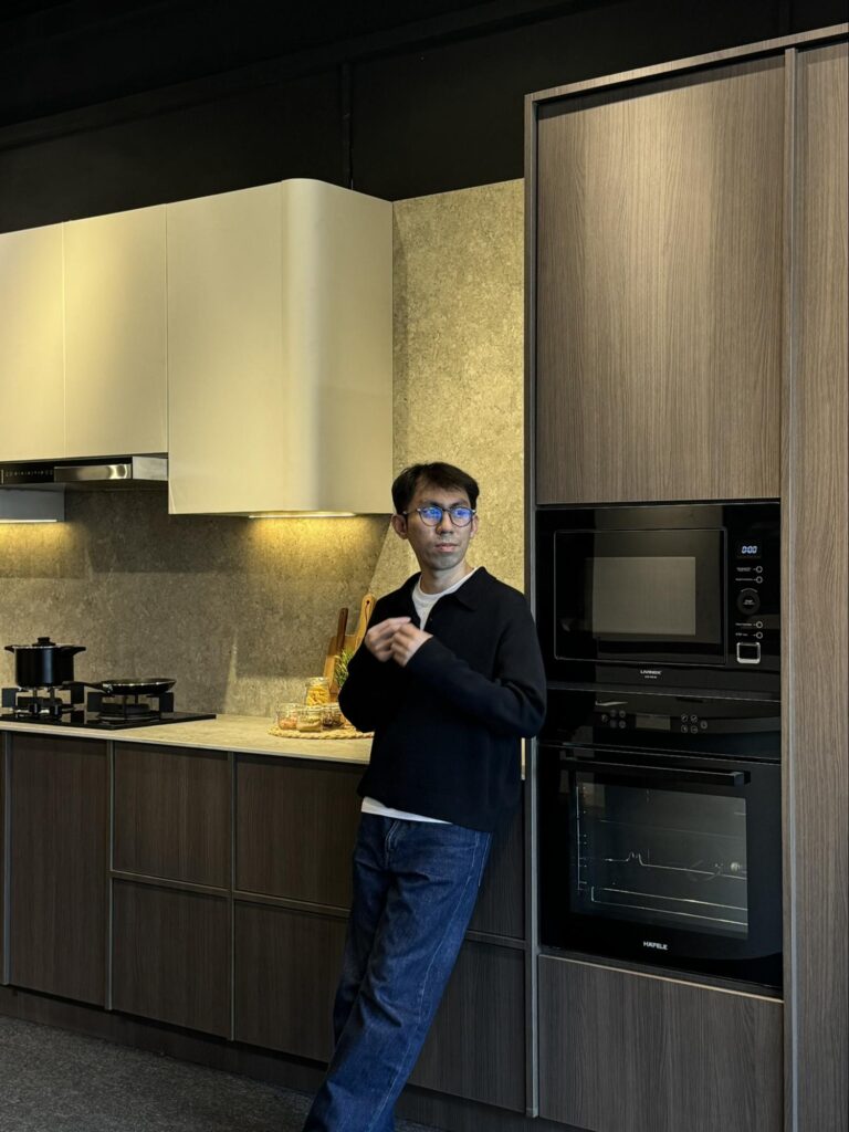 Nest Butler designer standing beside a modern kitchen featuring bespoke cabinetry, built-in appliances, and Cosentino stone surfaces.