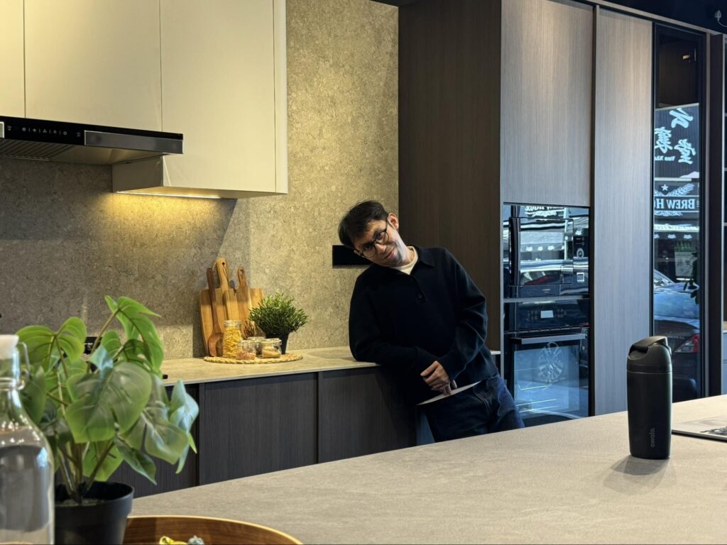Nest Butler designer Hazrin Hazinor beside a modern kitchen featuring Cosentino stone surfaces and bespoke cabinetry at the Kota Damansara showroom.